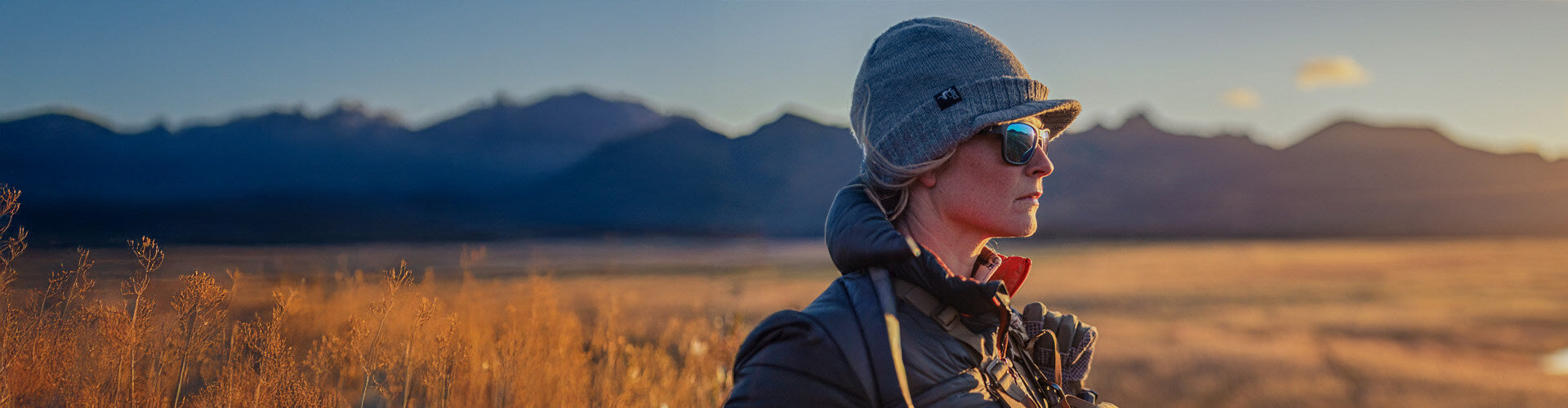 Person standing in a field with mountains in the background