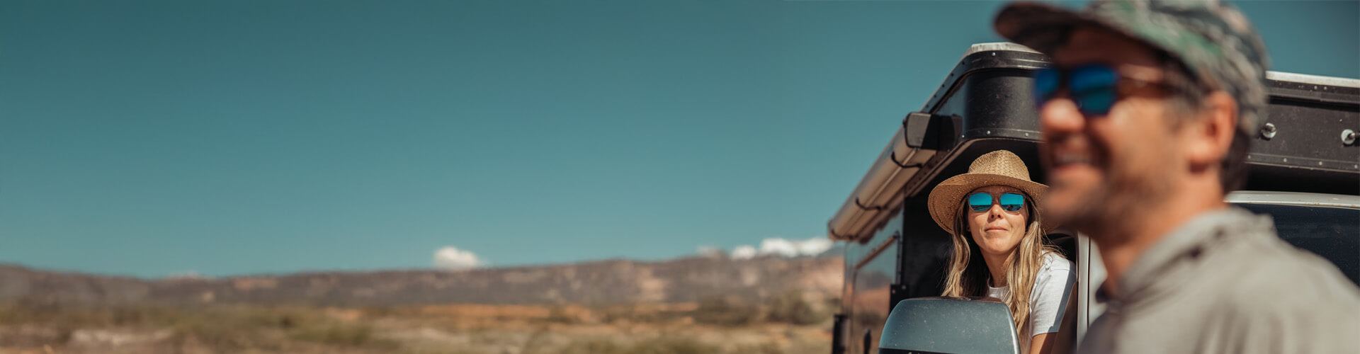 Two people in a vehicle with a scenic landscape in the background