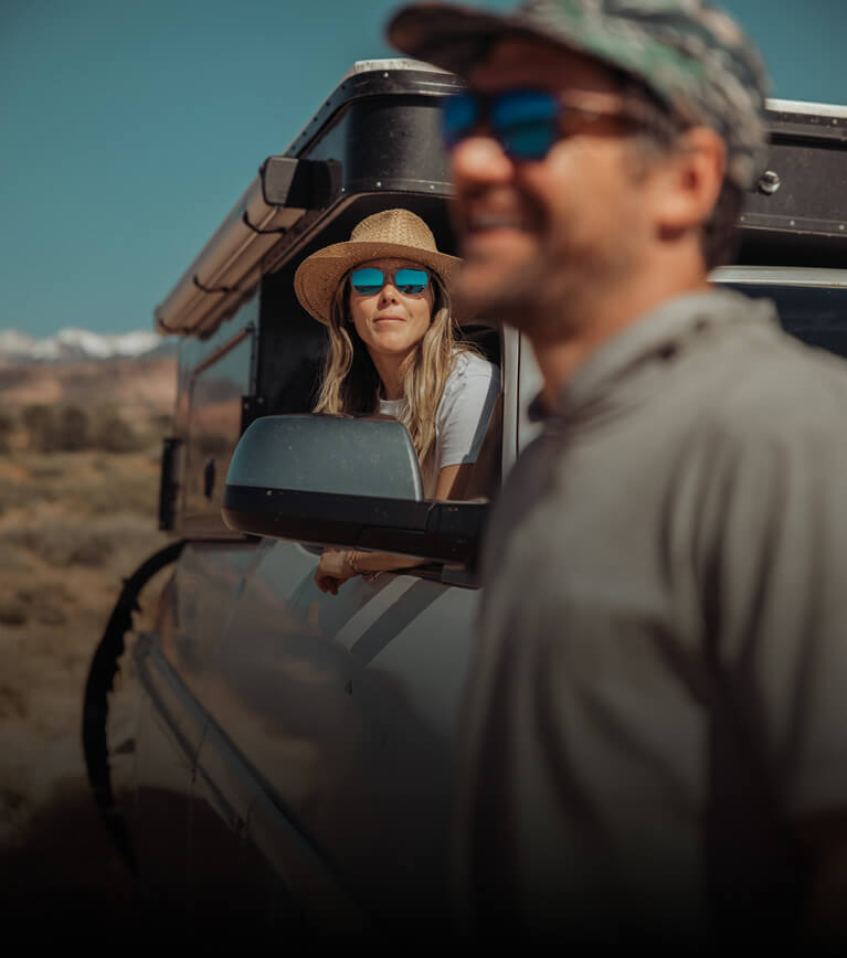 Two people in a vehicle with mountains in the background